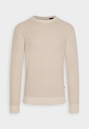 Maglione beige lavorato a maglia con scollatura rotonda e maniche lunghe a raglan. Presenta polsini e orlo a coste, una texture liscia e dettagli sottili.