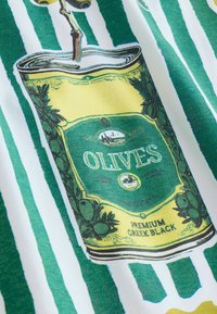 Prémium görög fekete olívabogyók konzervje zöld és sárga címkével, olívabogyó illusztrációkkal, fehér és zöld csíkos szövet háttéren.