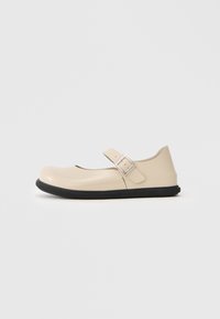 Scarpa Mary Jane beige con punta rotonda, cinturino regolabile e suola in gomma nera. Finitura lucida e liscia con design minimalista.