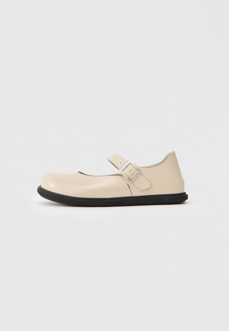 Scarpa Mary Jane beige con punta rotonda, cinturino regolabile e suola in gomma nera. Finitura lucida e liscia con design minimalista.