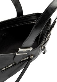 Czarna skórzana torebka z przestronnym wnętrzem, srebrnymi metalowymi elementami oraz zewnętrznymi kieszeniami na zamek dla dodatkowej funkcjonalności.