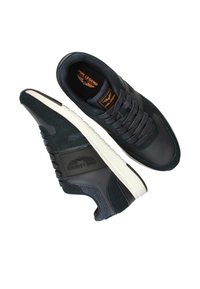 Donkerblauwe sportschoenen van suede en leer, met een gestructureerde afwerking, ronde neus, logo-detail en een witte rubberen zool.