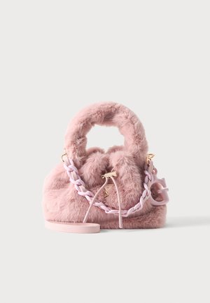 Rosa flauschige Handtasche mit rundem Griff, geflochtenem Kettenriemen, Kordelzugverschluss und kleinem angebrachtem Logoanhänger auf einfachem Hintergrund.