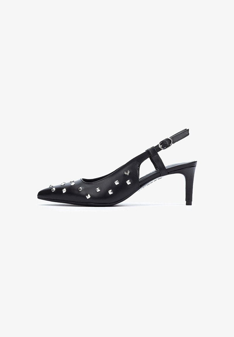 Zapato de tacón negro tipo slingback, hecho de piel suave con punta afilada. Presenta tachuelas plateadas a lo largo del lateral y un tacón delgado. Incluye una correa ajustable.