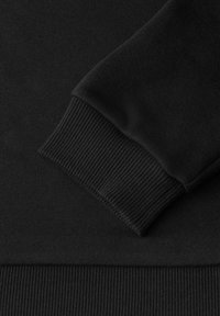 Tessuto di felpa nera che mostra un primo piano del polsino e dell'orlo a coste. La texture è liscia con un colore uniforme e un pattern a maglia stretto.