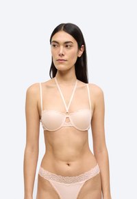 Σουτιέν σε απαλό ροζ με δαντελένιες λεπτομέρειες και γεωμετρικό μοτίβο. Διαθέτει ρυθμιζόμενους ιμάντες και κεντρικό διακοσμητικό στοιχείο. Συνοδεύεται από τόνγκα με δαντέλα που ταιριάζει.