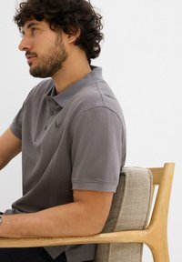 Polo grigio con colletto, maniche corte e pattina con due bottoni. Texture liscia e dettagli con logo ricamato sul lato sinistro del petto.