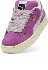 Ljubičaste suede tenisice s bijelim kožnim naglascima, teksturiranim kremastim gumiranim potplatima i višebojnim prugastim vezicama. Puma logo na jeziku i sa strane.