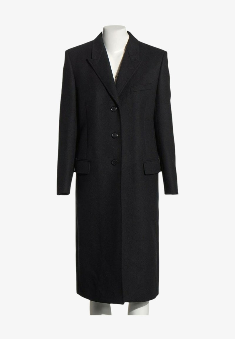 Long manteau formel noir avec trois boutons, col à revers cranté et poches à rabat, présenté sur un mannequin blanc.