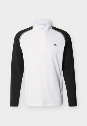 Haut pour homme à manches longues avec demi-fermeture éclair, devant blanc, manches noires, col montant et petit logo sur la poitrine.