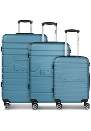 Three lightweight turquoise hard-shell suitcases of varying sizes, featuring horizontal ridges, black accents, and multi-directional wheels.