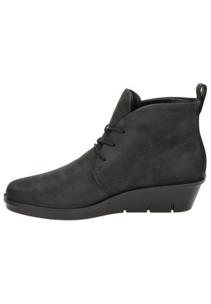 Bottine noire en daim avec talon compensé, lacets sur le devant et languette à l'arrière pour un enfilage facile.