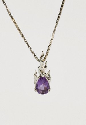 Přívěsek ve tvaru stříbrného plamene držící broušený fialový drahokam ve tvaru kapky na stříbrném řetízku.