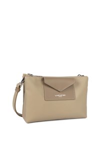 Borsa a tracolla sintetica beige con texture liscia, chiusura con zip e dettaglio a soffietto triangolare. Presenta una tracolla e logo in argento.