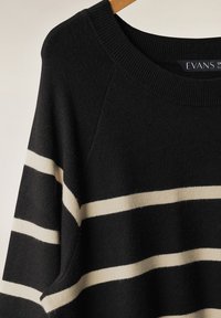 Maglione a righe nere con ampie righe color crema, colletto a coste e texture morbida. Maniche raglan e design dal fitting casual.