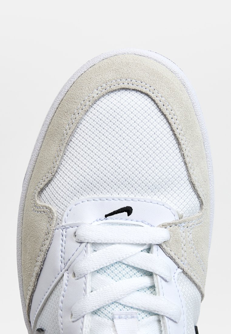 Weißer Sneaker aus Mesh- und Wildledermaterial, strukturiertes Design, Schnürverschluss und schwarzes Logo-Detail auf der Zunge. Klassische Form.