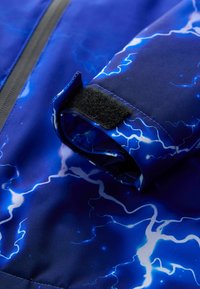 Blue fabric with a lightning pattern, featuring a rolled sleeve and black Velcro fastener. Smooth texture with a shiny finish.