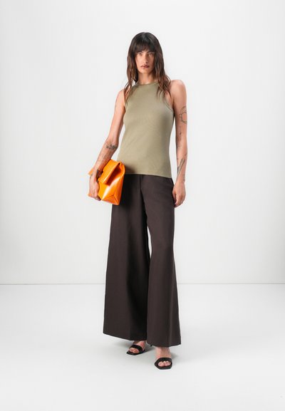 Olive green ribbed tank top, brown wide-leg trousers, and an orange folded clutch. Model wears black heeled sandals.