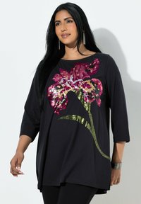 Černý top s dlouhým rukávem s květinovým vzorem z flitrů v růžové, zlaté a zelené barvě. Měkká látka s volným střihem a postranními rozparky.