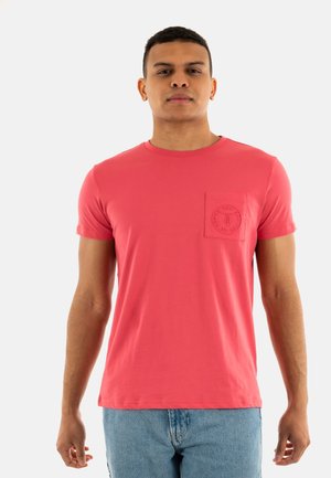 T-shirt à manches courtes et col rond en corail rose, avec une poche texturée et un détail de logo circulaire. Fabriqué en coton doux.