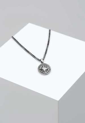 Silberne Anhänger-Halskette mit einem kreisförmigen Kompassdesign, detailreicher Gravur und strukturiertem Kettenband. Auf einem geometrischen Ständer präsentiert.