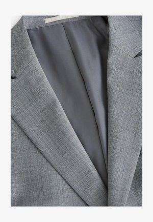 Grauer Anzugjacke mit einem strukturierten Außenstoff; verfügt über ein glattes graues Futter und Einschlagrevers. Nahaufnahme des Innenlebens.