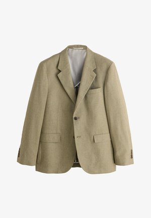 Mani che aggiustano il polsino di una giacca beige con bottoni scuri, indossata sopra una camicia azzurra a quadri.