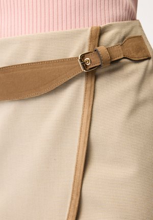 Béžová a světle hnědá kostkovaná sukně s páskem z opálené semiše se zlatou sponou, nošená s růžovým žebrovaným topem.