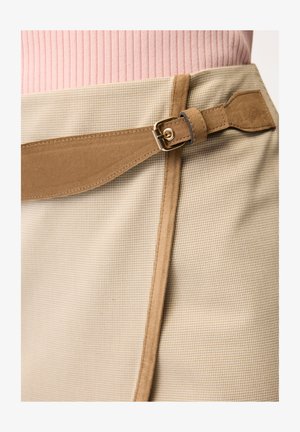 Beiger und hellbrauner karierter Rock mit einem hellbraunen Wildledergürtel mit einer goldenen Schnalle, getragen zu einem rosa gerippten Oberteil.