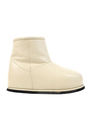 Beige læderankelstøvle med rundet tå og flad sort sål, vist fra siden på en hvid baggrund.