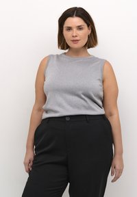 Srebrni top bez rukava s rebrastom teksturom, uparen s crnim hlačama visokog struka koje imaju detalj dugmadi na struku.