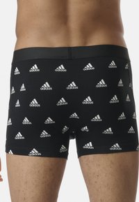 Boxer in cotone nero realizzati in morbido tessuto, con un motivo ripetuto del logo Adidas bianco. Vita elastica per comfort e vestibilità.