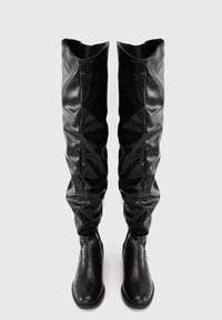 Botas de imitación de cuero negro hasta la rodilla con un diseño holgado, textura suave y cremalleras laterales, que presentan una resistente puntera redonda y un tacón bajo.