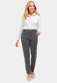 Grijze maatbroek gemaakt van stof met een gladde textuur, gecombineerd met een witte overhemden. De outfit wordt aangevuld met beige schoenen.