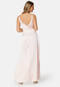 Abito lungo in satin rosa pallido con schiena drappeggiata, spalline sottili e dettagli in pizzo sullo scollo. Tessuto liscio con una silhouette fluida.