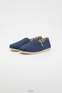 Blauwe canvas instapschoenen met een afgeronde neus, beige rubberen zool en een zigzagpatroon aan de binnenkant. Heeft gestikte details op het bovenwerk.