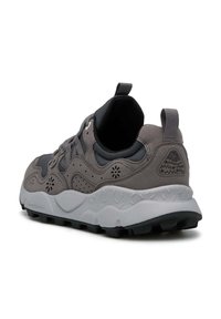 Scarpa atletica grigia con un mix di materiale scamosciato e sintetico, che presenta una suola intermedia bianca texturizzata, suola in gomma nera e un tassello sul retro per tirare.