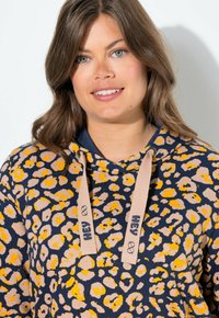 Sweat-shirt à capuche en marine avec imprimé léopard beige et jaune. Fabriqué en coton, avec des accents à cordon de serrage et une coupe décontractée.
