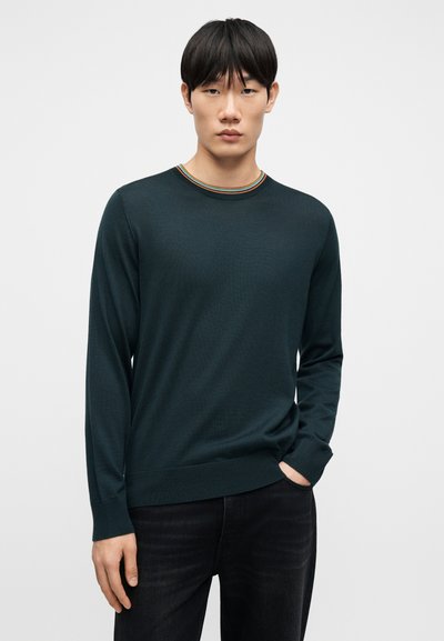 Pull en maille vert foncé avec un col rond, présentant un accent rayé multicolore au niveau du col. Manches longues et détail avec bord-côte à l'ourlet.