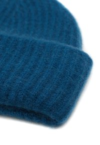 Gorro de punto azul hecho de lana suave, con una textura acanalada y un dobladillo, que resalta su apariencia acogedora.