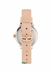 Reloj redondo con correa de cuero rosa claro y hebilla de metal. Cuenta con un fondo de caja de cristal que exhibe el mecanismo.