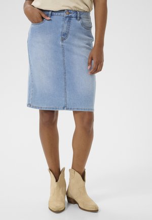 Lyseblå denimnederdel med tætsiddende talje, forlommer og knælængde. Sættes sammen med beige cowboystøvler for kontrast.