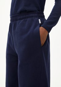 Marineblaue Jogginghose mit elastischem Bund, seitlichen Taschen und weichem Material; mit einem kleinen Markenetikett in der Nähe des Bundes.