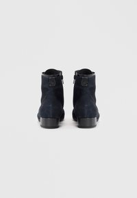 Bottines en suede bleu marine avec une finition lisse, bouts ronds, zips latéraux et petits talons carrés.