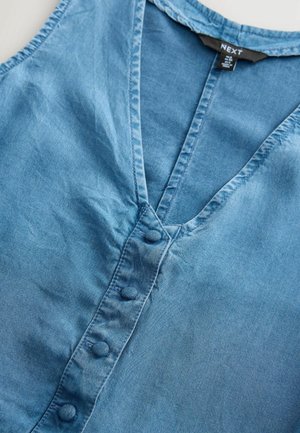 Denim plava košulja s V-izrezom, koja ima kopčanje sprijeda i teksturiranu tkaninu. Ovratnik i dugmad su također u usklađenoj plavoj boji.