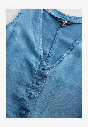 Denim plava košulja s V-izrezom, koja ima kopčanje sprijeda i teksturiranu tkaninu. Ovratnik i dugmad su također u usklađenoj plavoj boji.