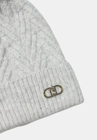 Gray knitted beanie with a herringbone pattern, featuring glitter accents and a gold logo hardware detail on the side.