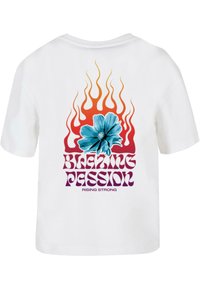 Valge T-särk, mille seljal on suur graafika sinise hibiski lille, oranžide ja kollaste leekidega ning tekst "PULBITSEV KIRG TÕUSEB TUGEVAKS."