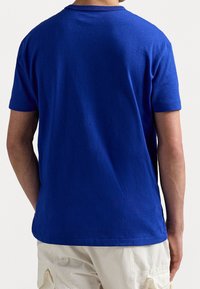 Camiseta de algodón azul real con cuello redondo y mangas cortas. La tela parece suave con un diseño de espalda sin costuras.