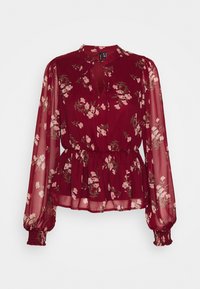 Blouse fleurie bordeaux en tissu léger et transparent. Elle présente des manches longues bouffantes, un col noué et une taille élastiquée pour une forme péplum.